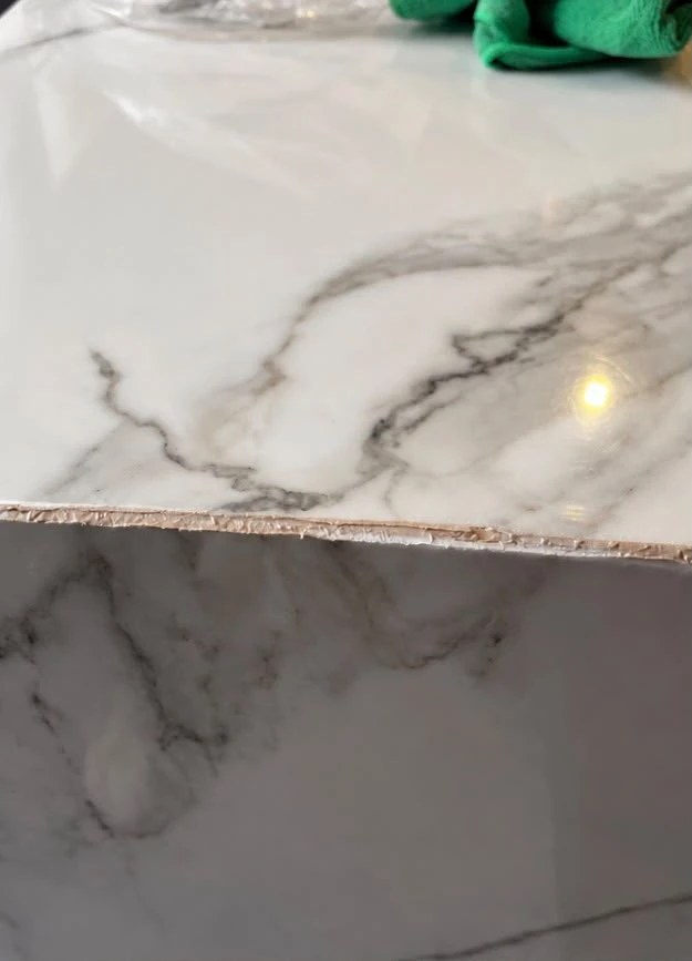 Chipped edge on a marble-effect household surface before repair