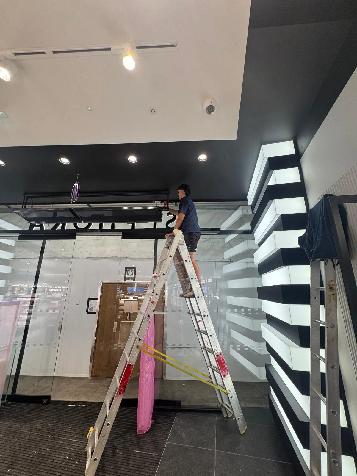 A team member working from a stepladder on a commercial fit-out